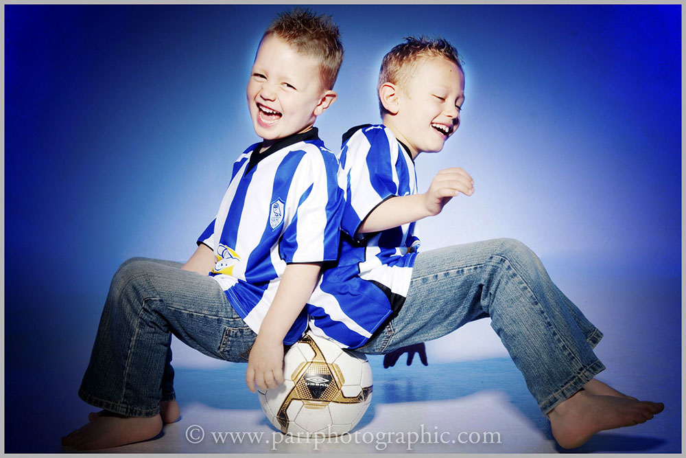 Studio Portrait of two boys sitting on a football