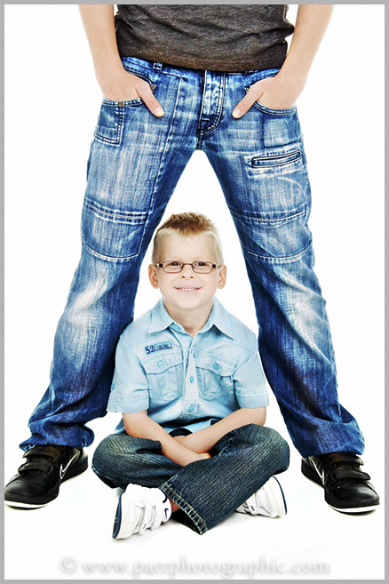 A boy sits under his dads legs