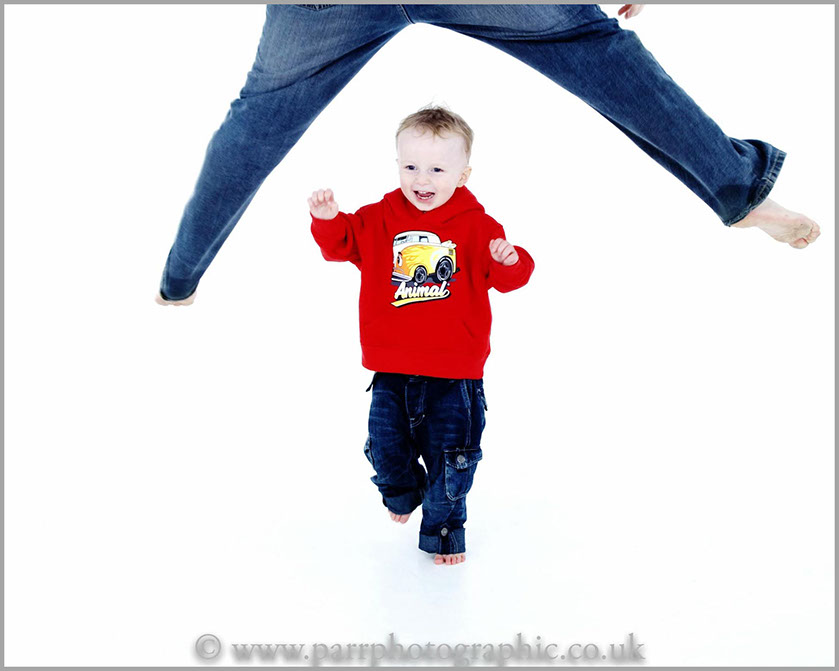 Studio Portrait of a child running through his dads legs 