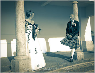 Bride and grrom stand opposite each other under The Belvedere Plymouth