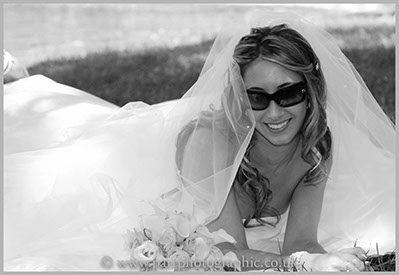Bride lies on the grass with bouquet of flowers infront