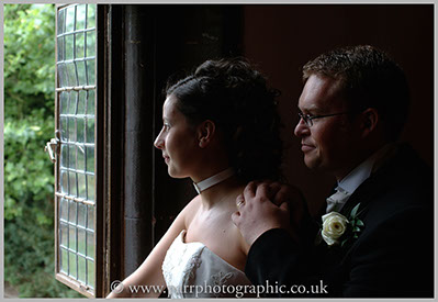 Bride and Groom look out of a old framed window