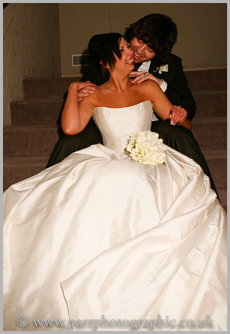 Bride and groom sit on the stairs laughing