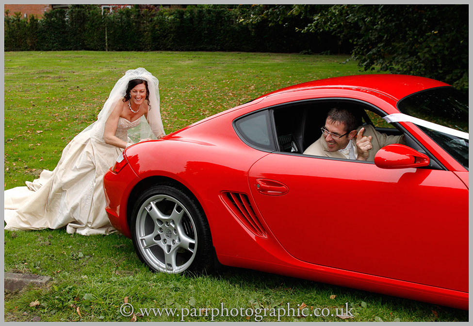 Bride pretends to push the wedding car of the grass