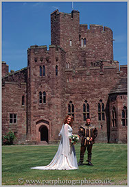 Bride and Groom stand in front of Peckforton Castle Chester